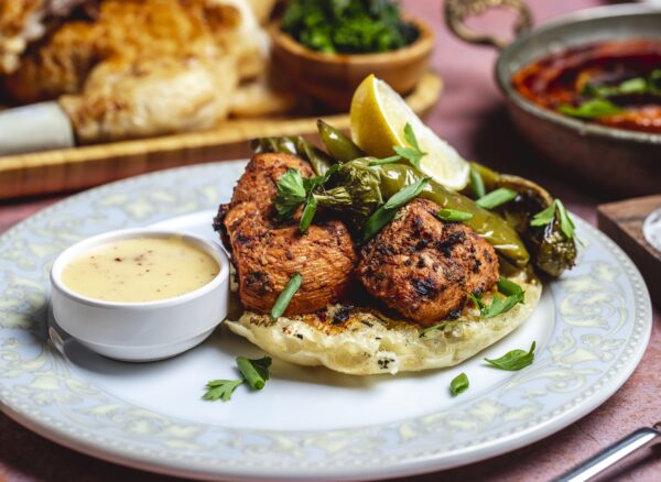 crilled chicken on bread piece greens pepper sauce spices side view APPOLO CHICKEN